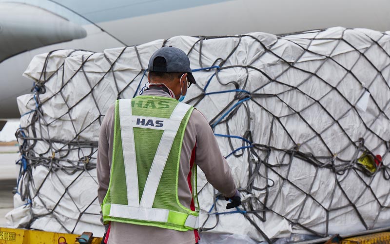 A staff wearing a Hong Kong Airport Services safety vest checking a cargo shipment