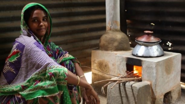A Bangladesh girl in traditional clothing sitting next to a stove