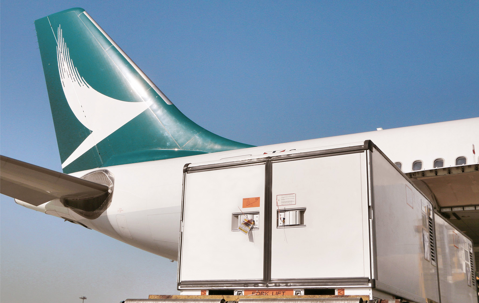 A Cathay Pacific tailfin with a container being loaded